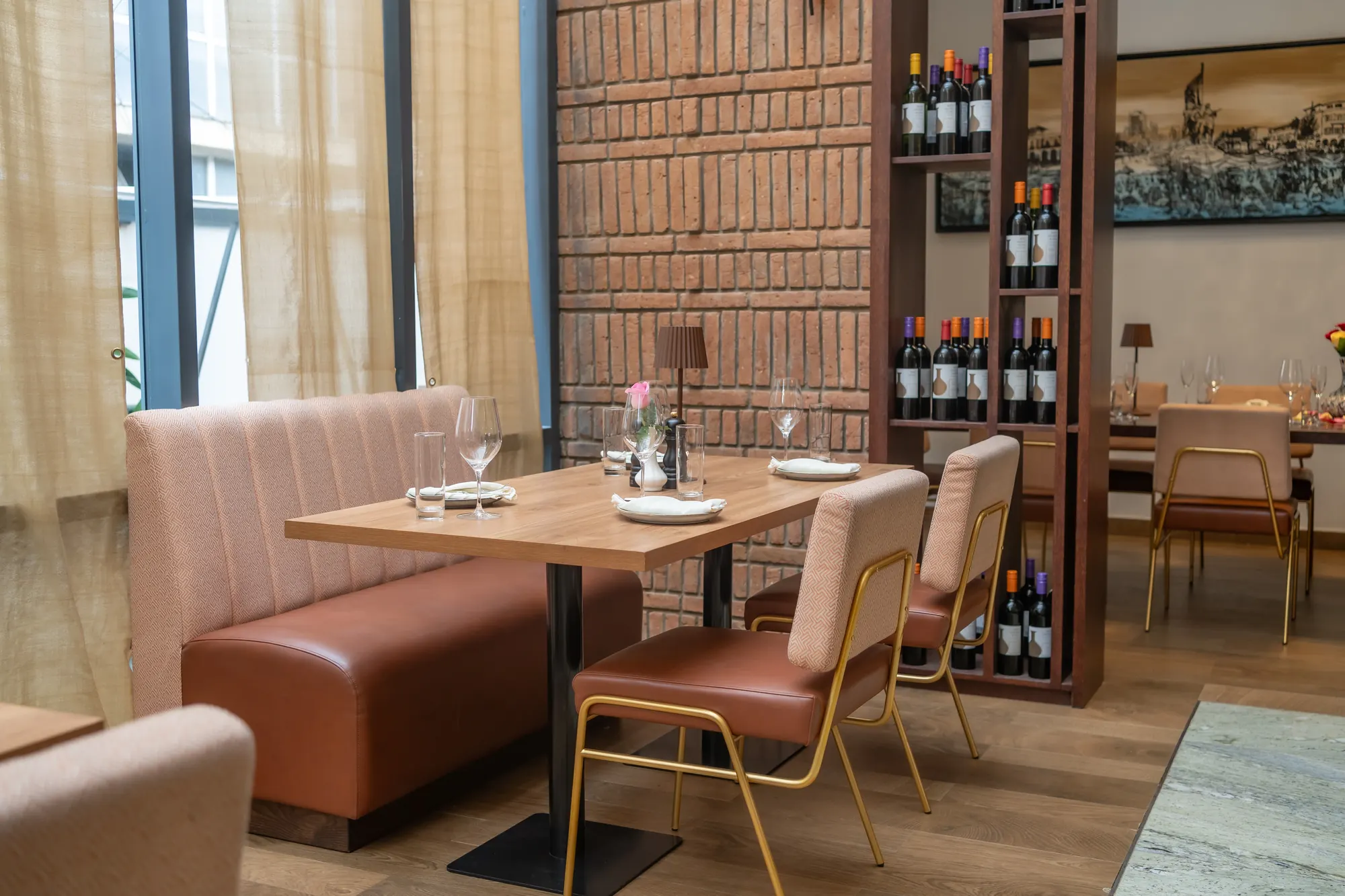 Dining room with banquette seating, a brick wall and the wine shelf