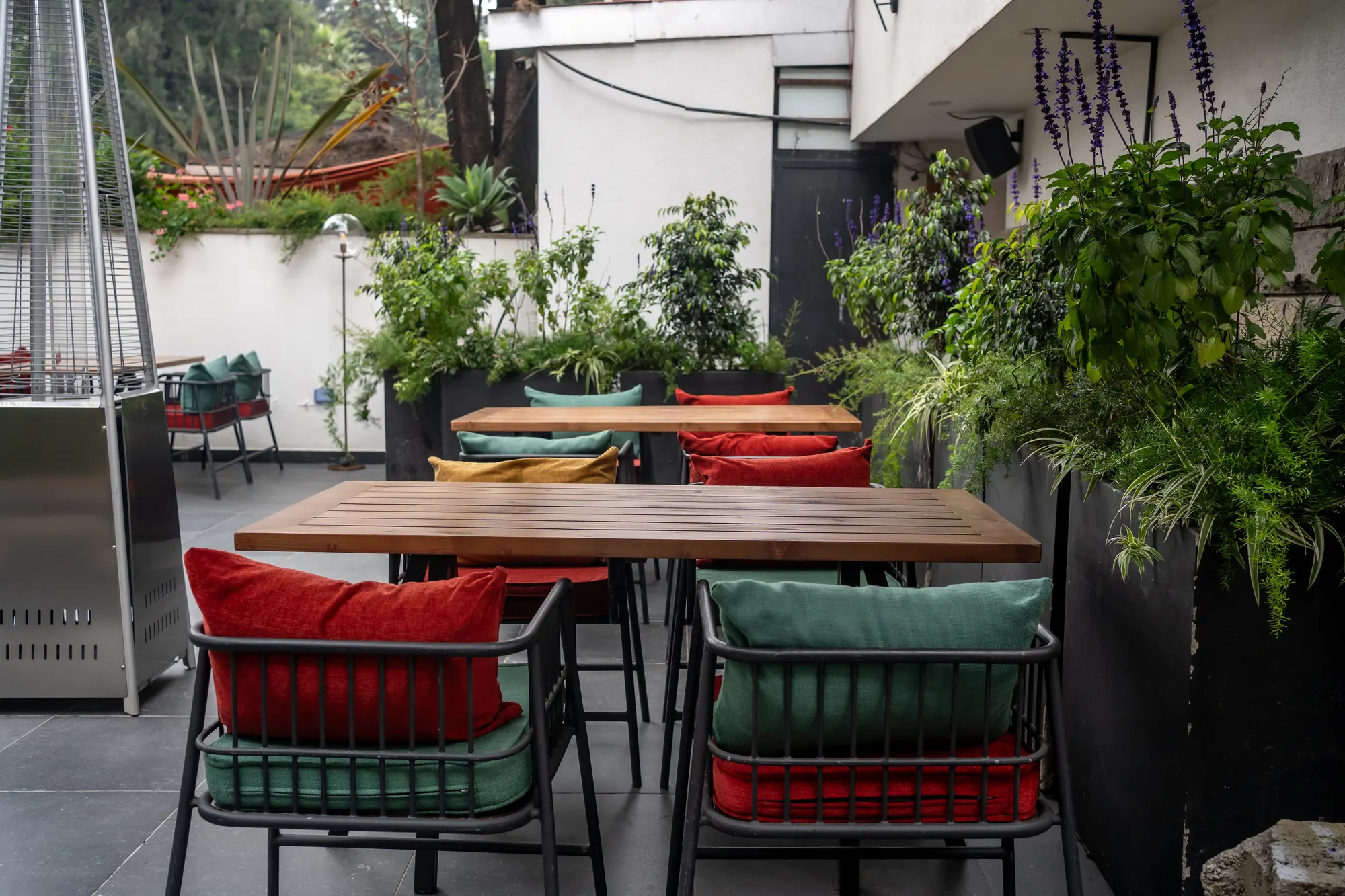Courtyard tables with red and green cushions among plants