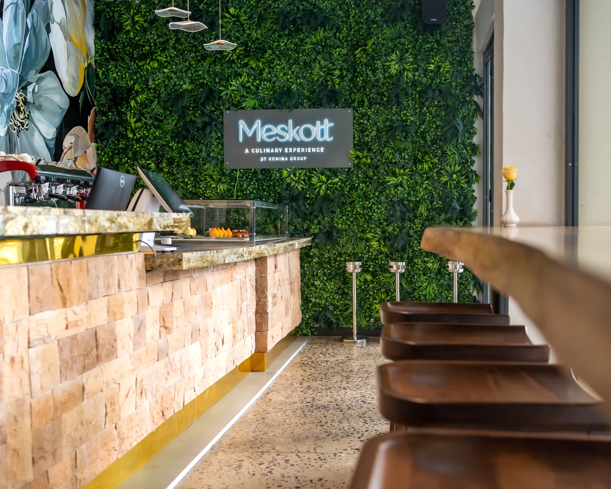 Stone-clad bar counter and stools before the Meskott green wall