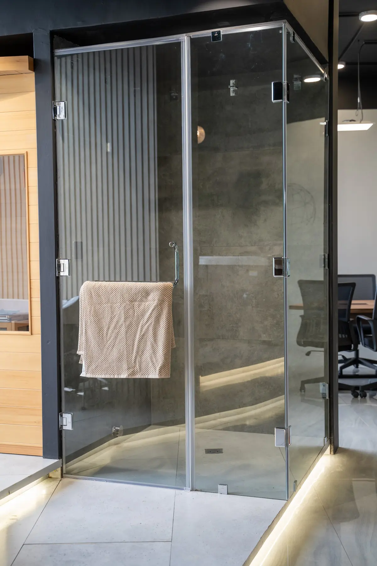 A frameless glass shower enclosure with a towel bar