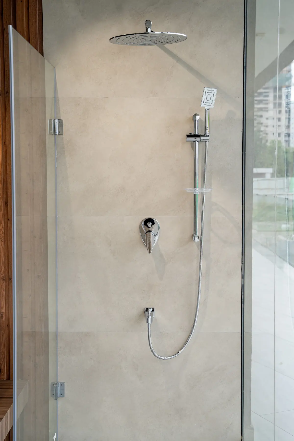 An overhead rain shower with a hand shower on a marble wall